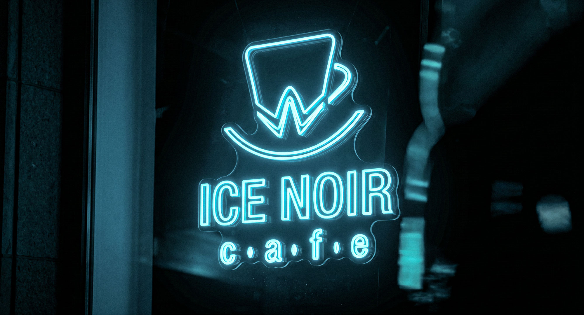 Ice Noir Cafe neon-style brand sign glowing in cyan on a dark cafe facade